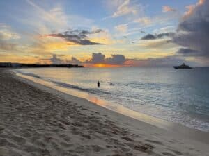 A breathtaking sunset on an Anguilla beach with a boat peacefully lingering in the background.