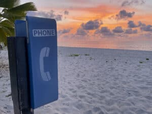 An Anguilla phone booth on the beach at sunset.