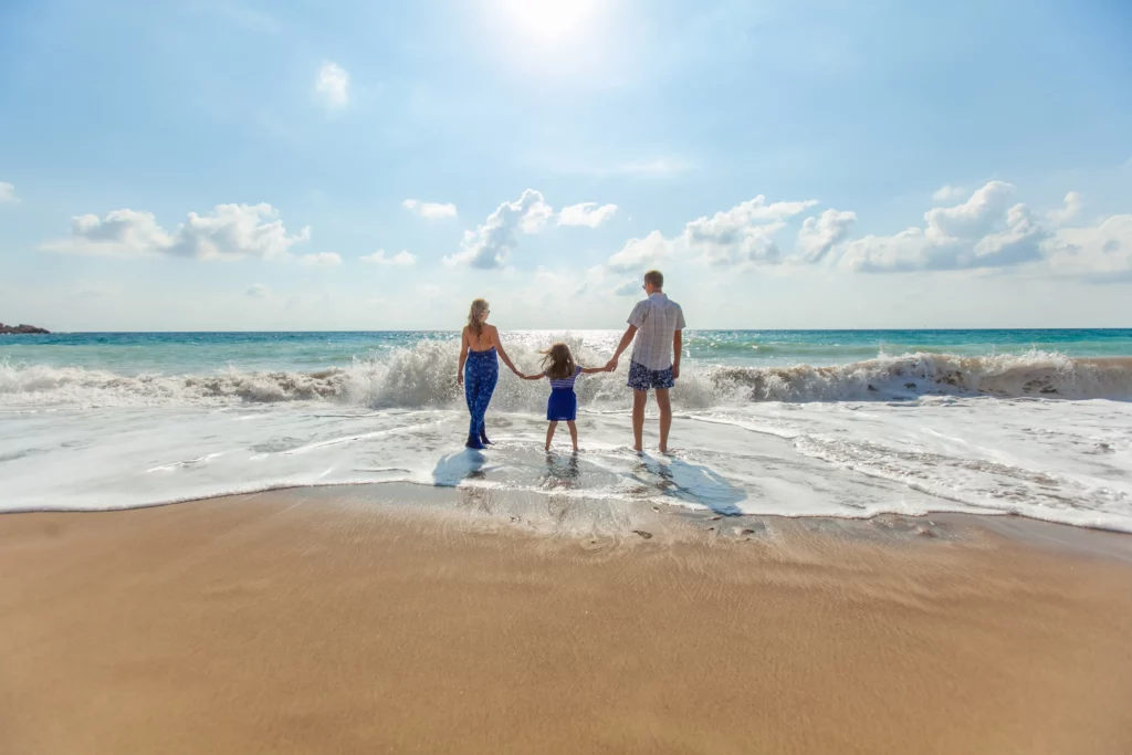 A family is standing on the beach with their hands in the sand.